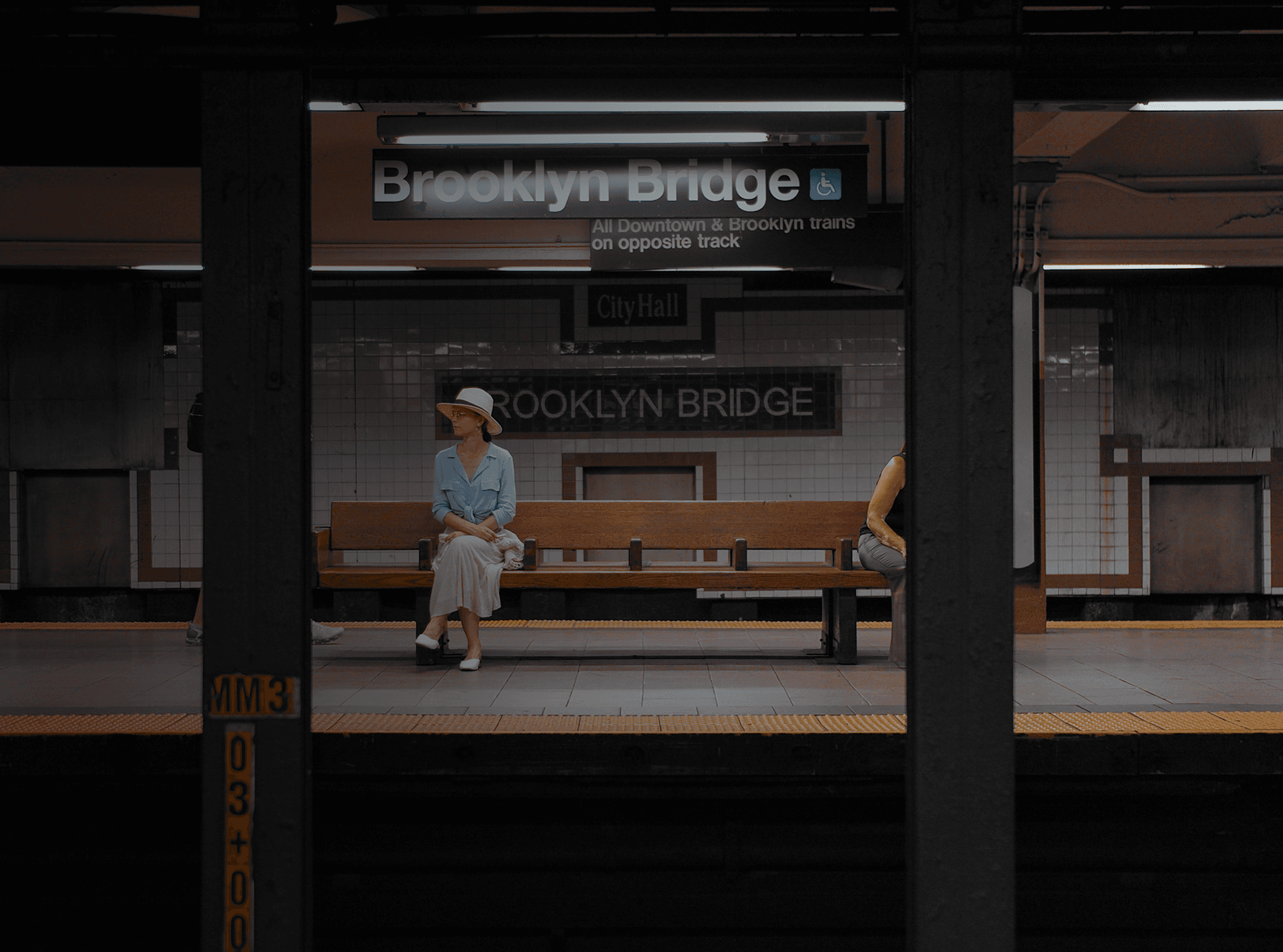 Uma mulher sentada em um banco em uma estação de metrô