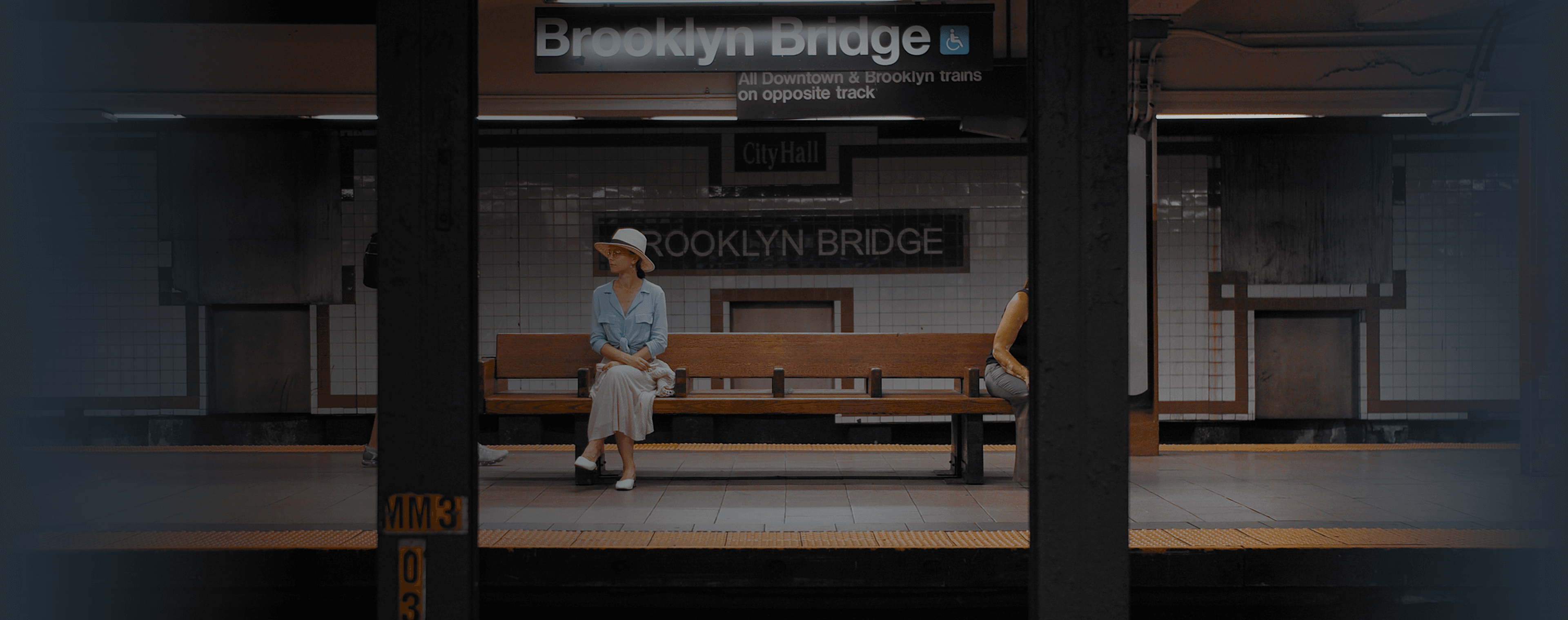 Uma mulher sentada em um banco em uma estação de metrô