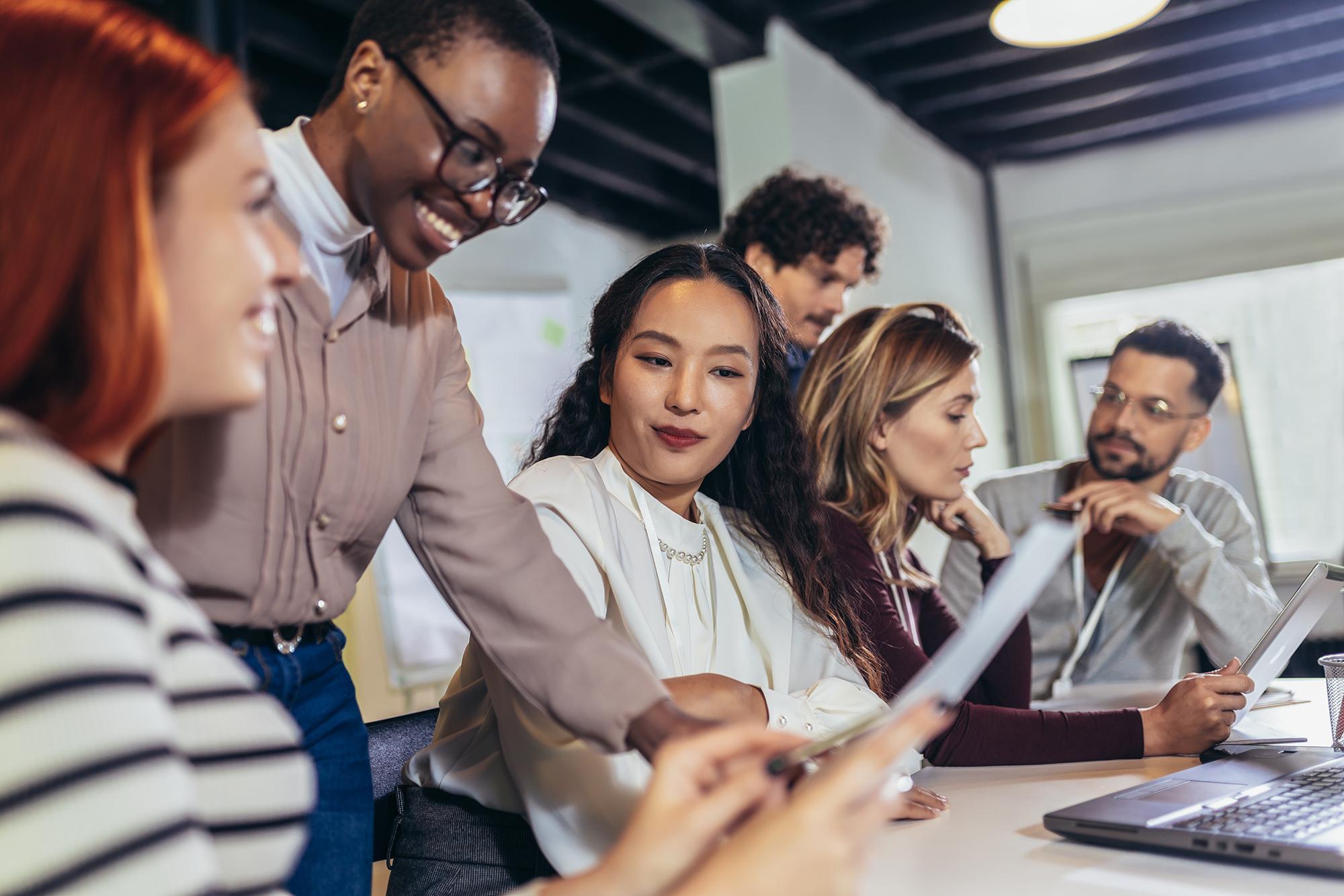 Grupo de profissionais colaborando em uma reunião, destacando os programas de aprendizado de idiomas da Rosetta Stone para empresas, com o objetivo de aprimorar a comunicação e as habilidades no ambiente de trabalho.