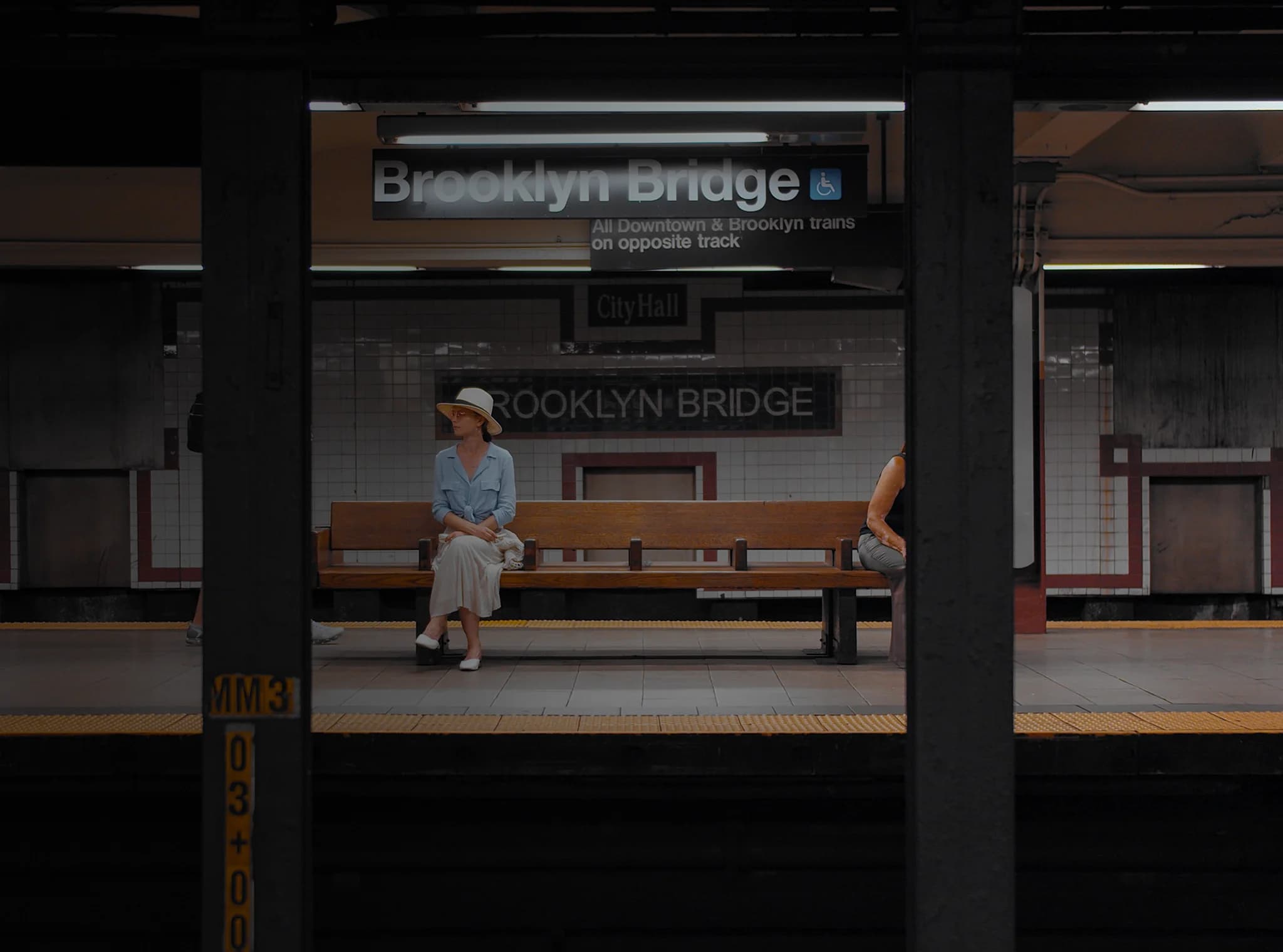 Uma mulher sentada em um banco em uma estação de metrô