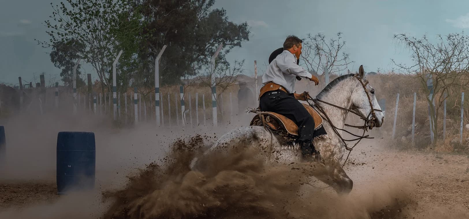 Cavaleiro em traje tradicional gaúcho levanta poeira ao fazer uma curva. Sobreposta está a palavra espanhola "gaucho" com sua tradução em português, "cavaleiro habilidoso".